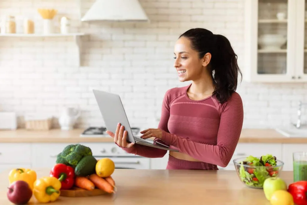 Woman browsing recipes on her laptop in the kitchen