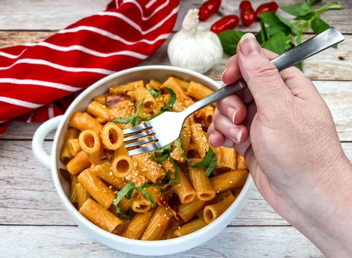 Rigatoni alla vodka on a white bowl with a fork.