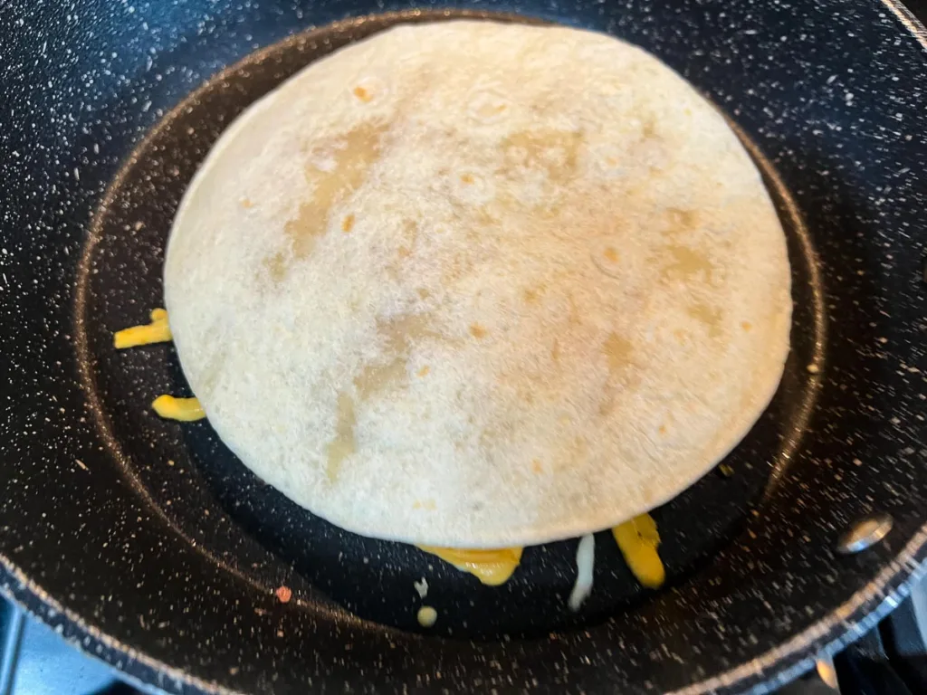 Top tortilla added to the queasadilla.