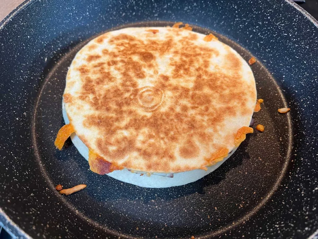 A golden brown quesadilla in a skillet.
