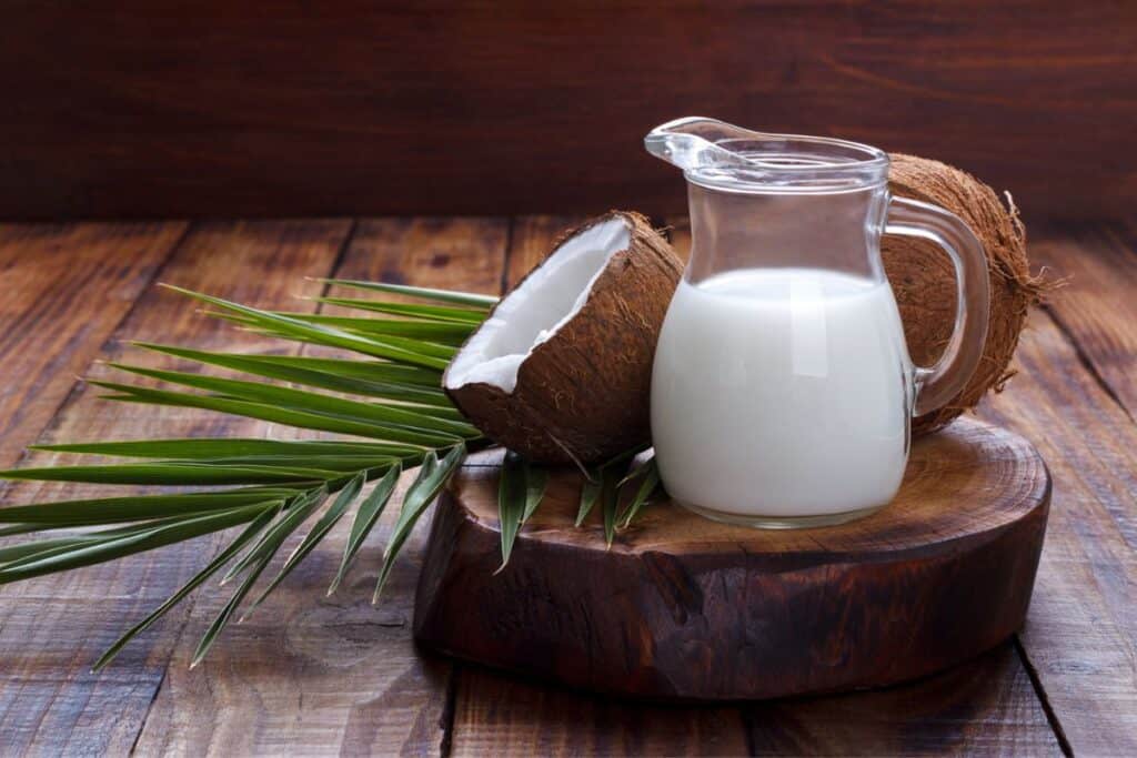 Coconut shell and milk on brown rustic background.