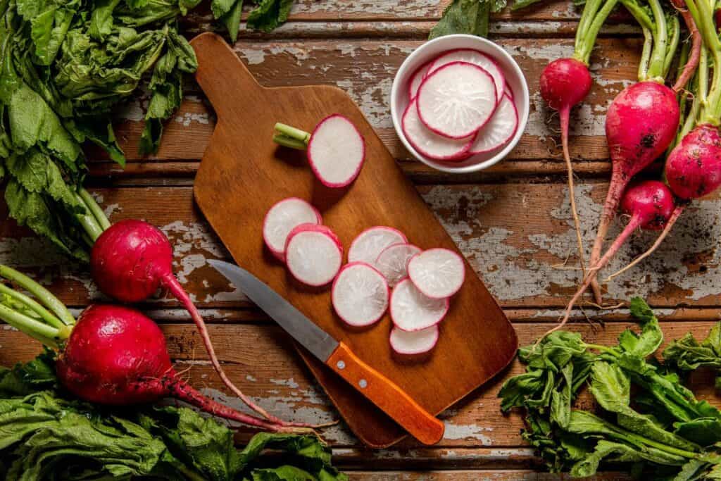 Radishes in chopping board with knife.