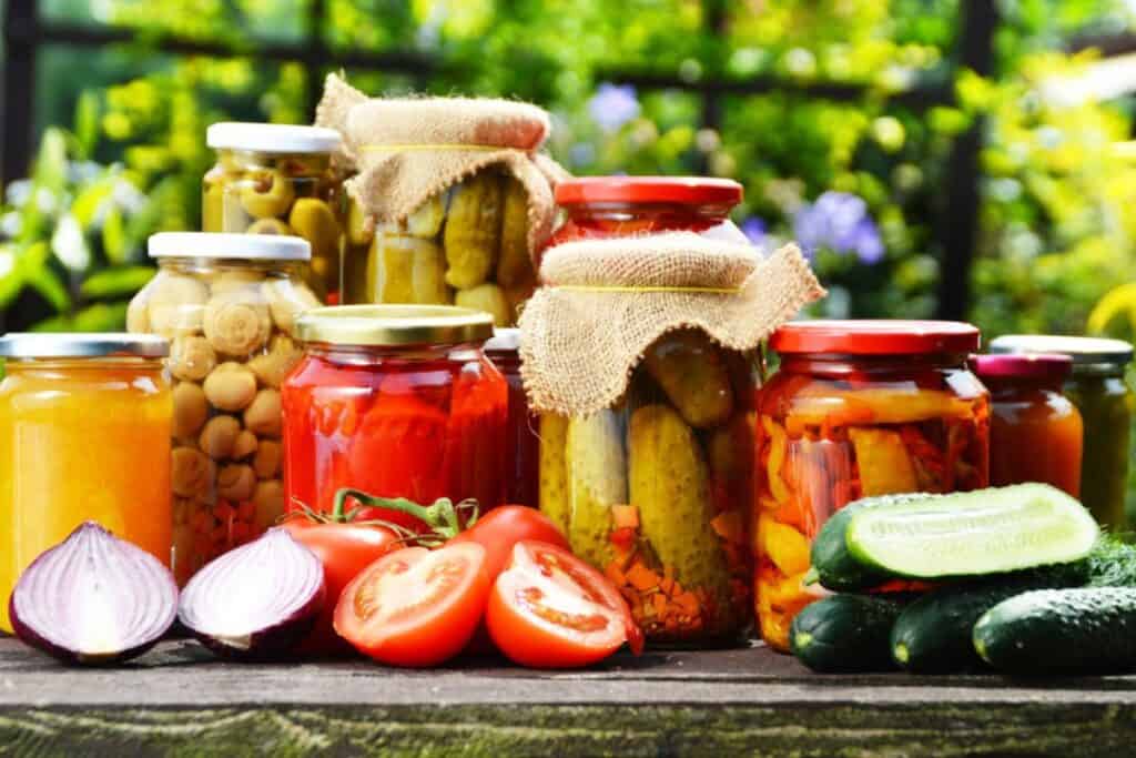 Variety of pickled foods in jars with ingredients.