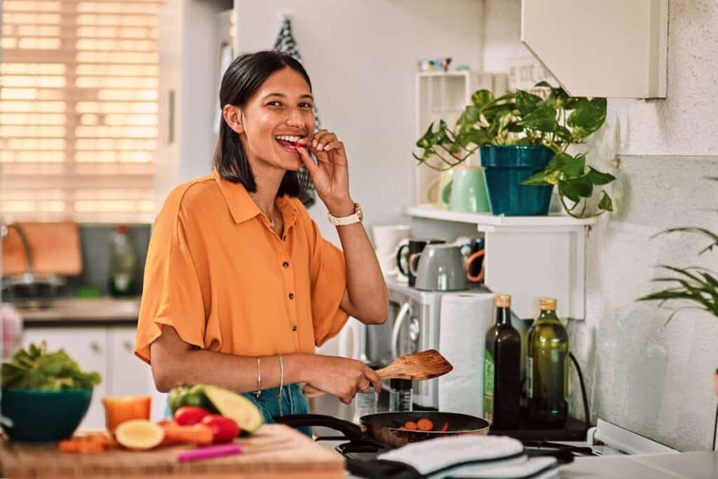 Woman tasting food in the kitchen.