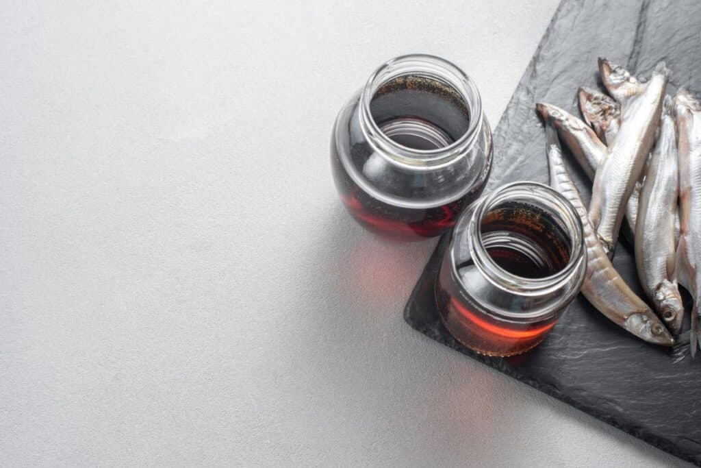 Fermented fish sauce is prepared by fermentation fish-salted garum sauce in a bottle on a gray background.