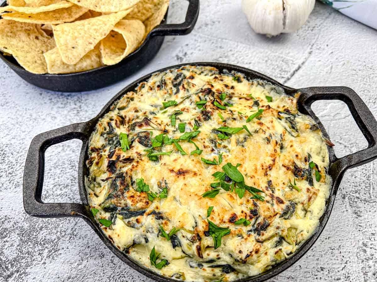 Copycat Applebee's Spinach-Artichoke Dip on a skillet next to chips.