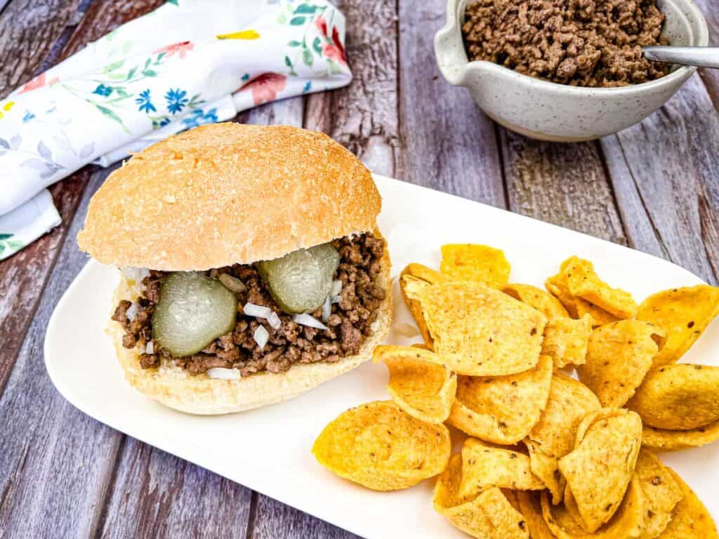 A plate of Copycat Maid-Rite Loose Meat Sandwich with chips.