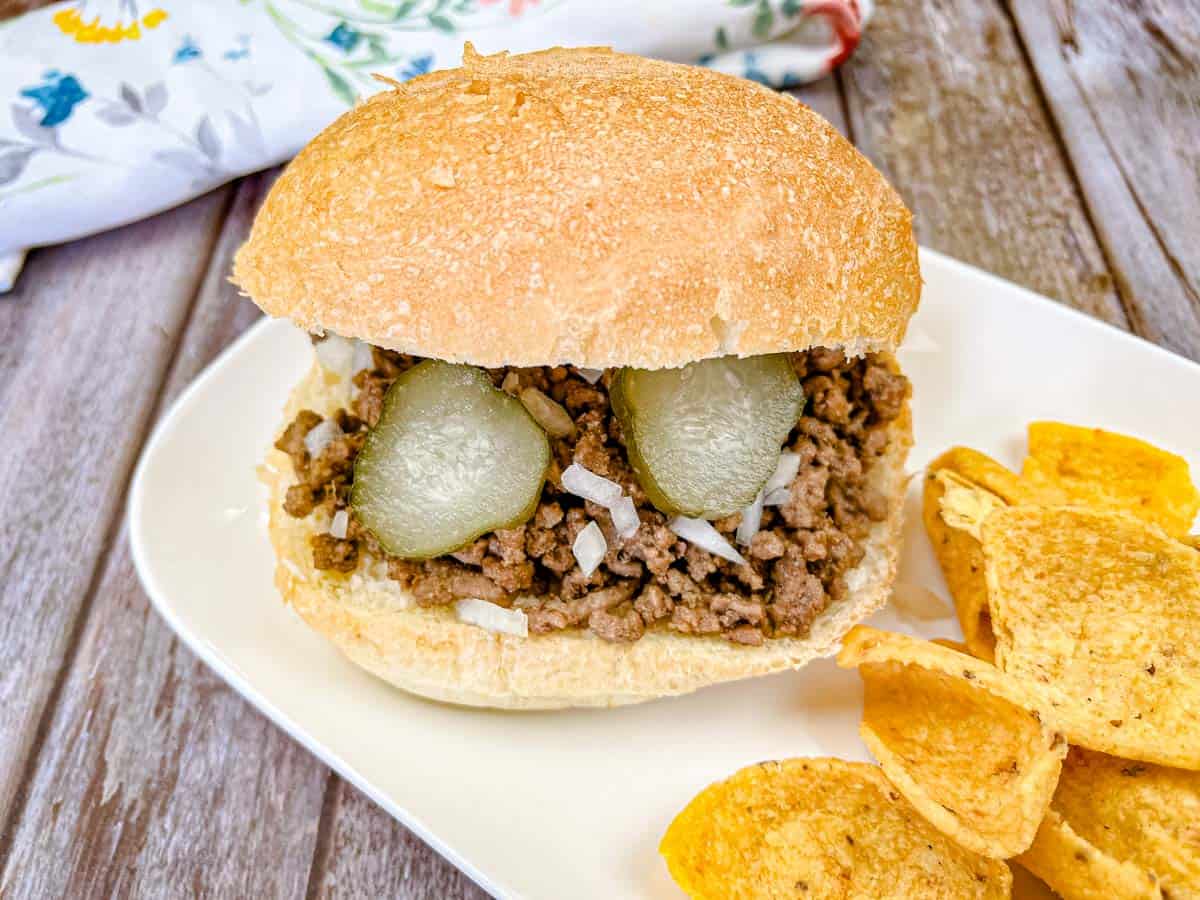 Copycat Maid-Rite Loose Meat Sandwich on a white plate with chips.