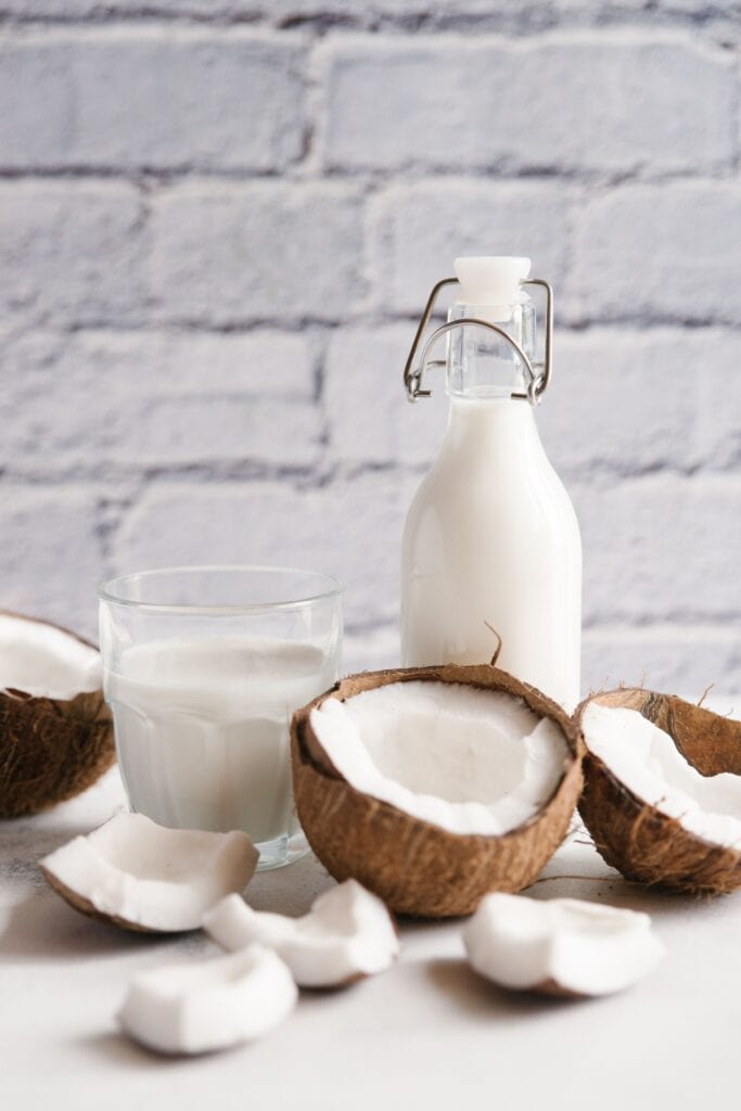 Coconut milk with broken coconut on a white table.