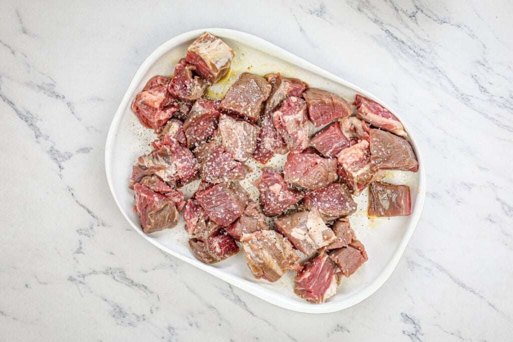 Season beef sirloin tips with salt and pepper, ensuring a thorough coating.