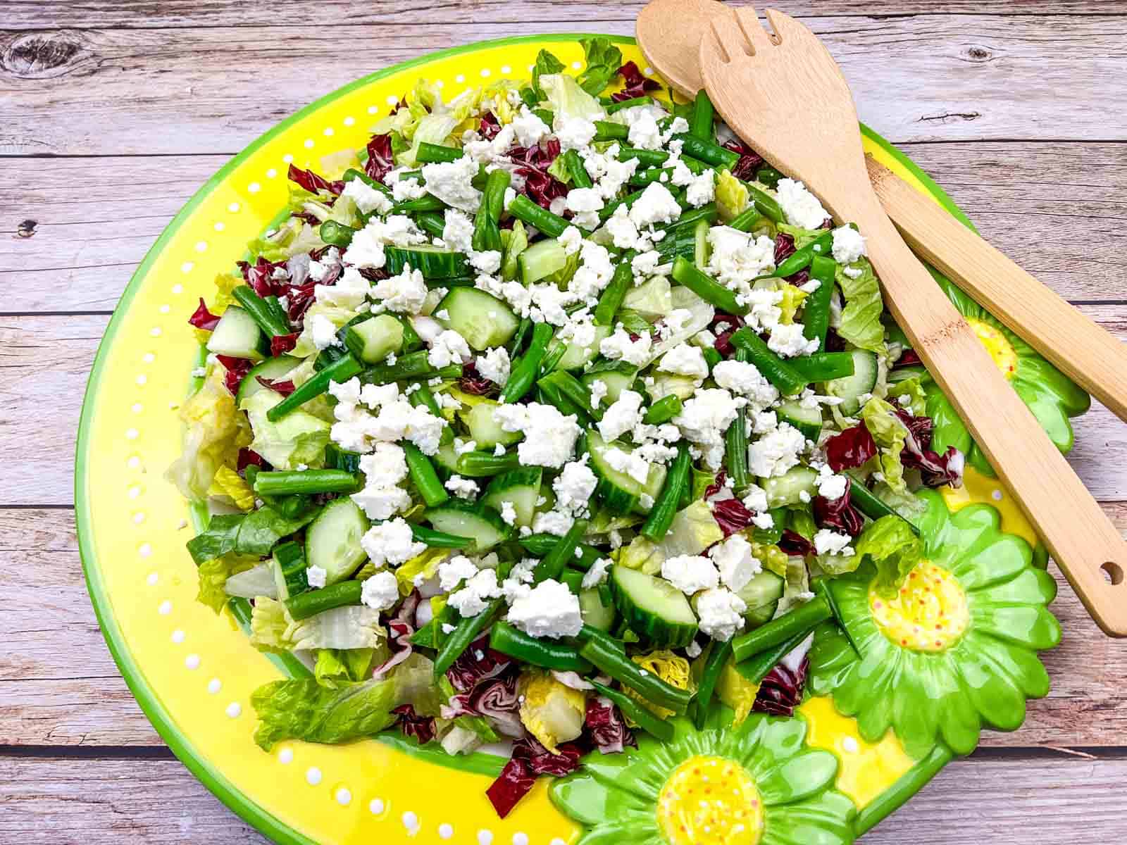 Mediterranean Chopped Salad with crumbled feta cheese, on a yellow plate with flower designs.