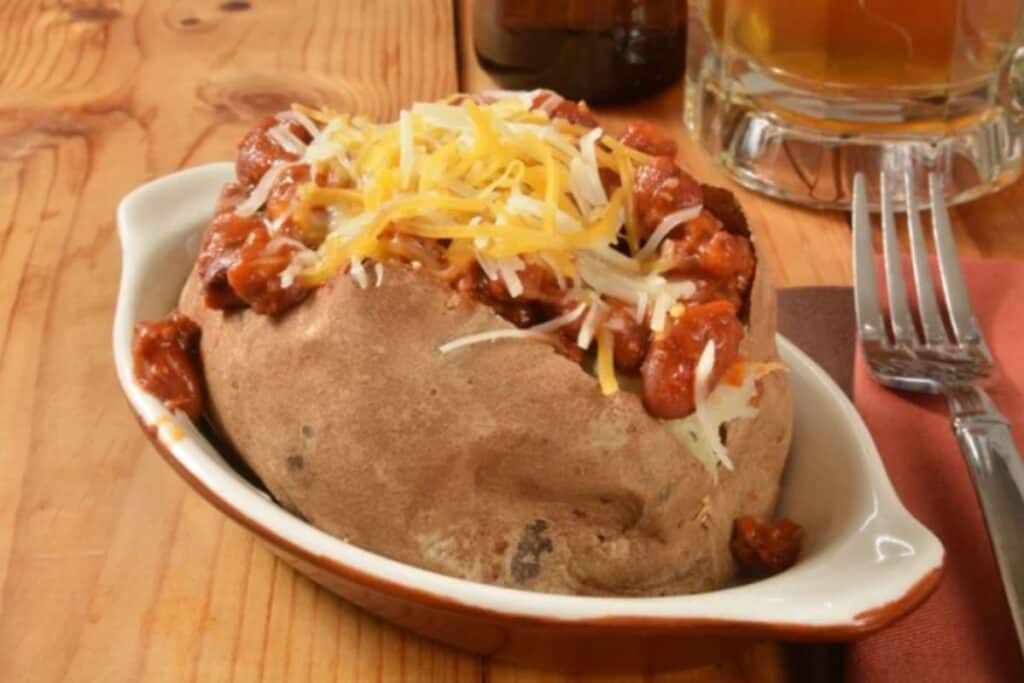 A bowl of baked potato with cheese on top.