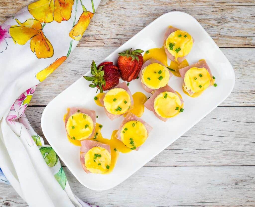 Top-down shot of Egg benedict bites on a white plate.