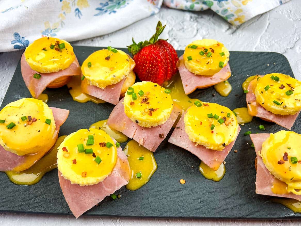 Nine pieces of Egg benedict bites on a slate plate.