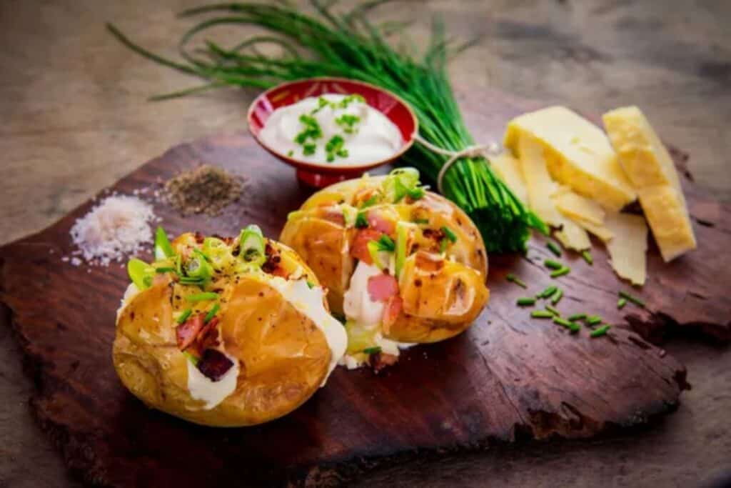 Two baked potatoes on a wooden board.