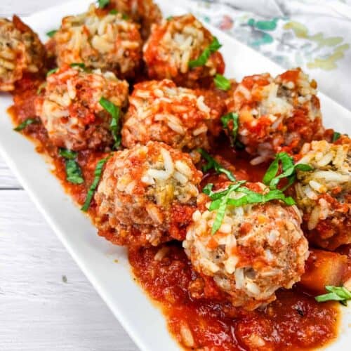 A plate of Slow Cooker Porcupine Meatballs with fresh basil on top.