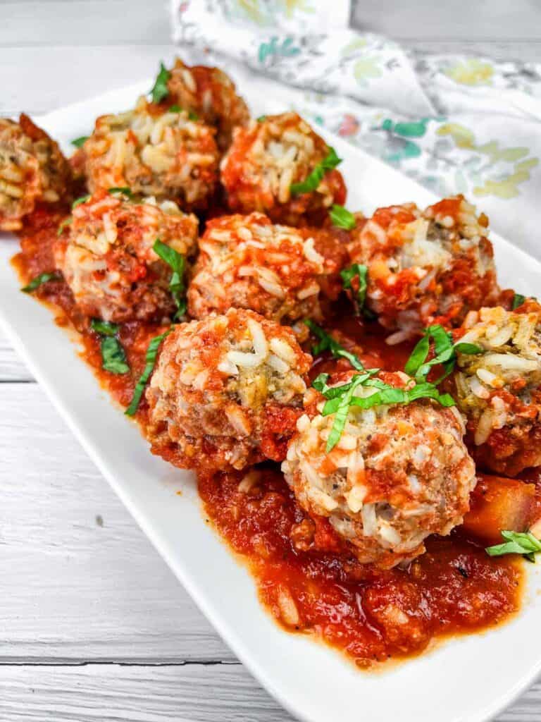 A plate of Slow Cooker Porcupine Meatballs with fresh basil on top.
