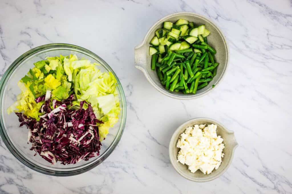 Mix green beans, cucumber, romaine, iceberg lettuce, and radicchio in a large salad bowl.