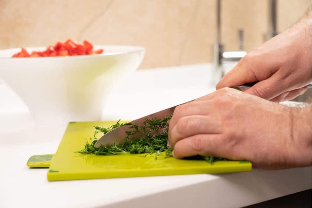 Cutting dill in a chopping board.