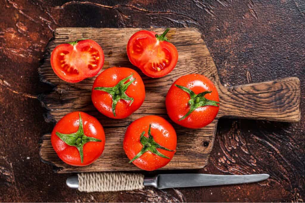 Tomatoes cut in half in a cutting board.