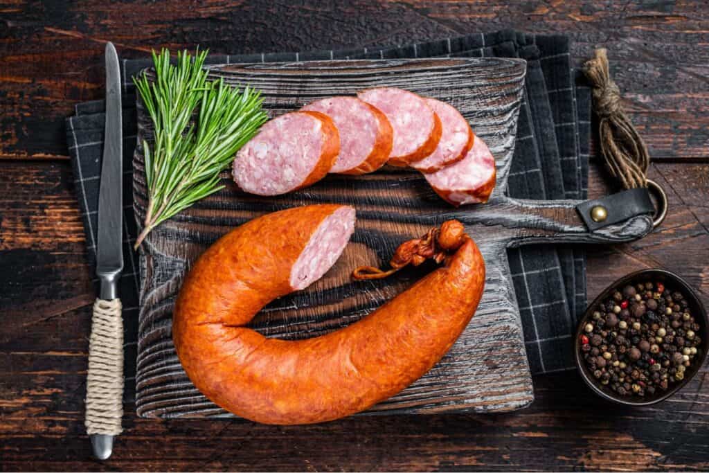 German Smoked sausage on a wooden rustic board with thyme. 