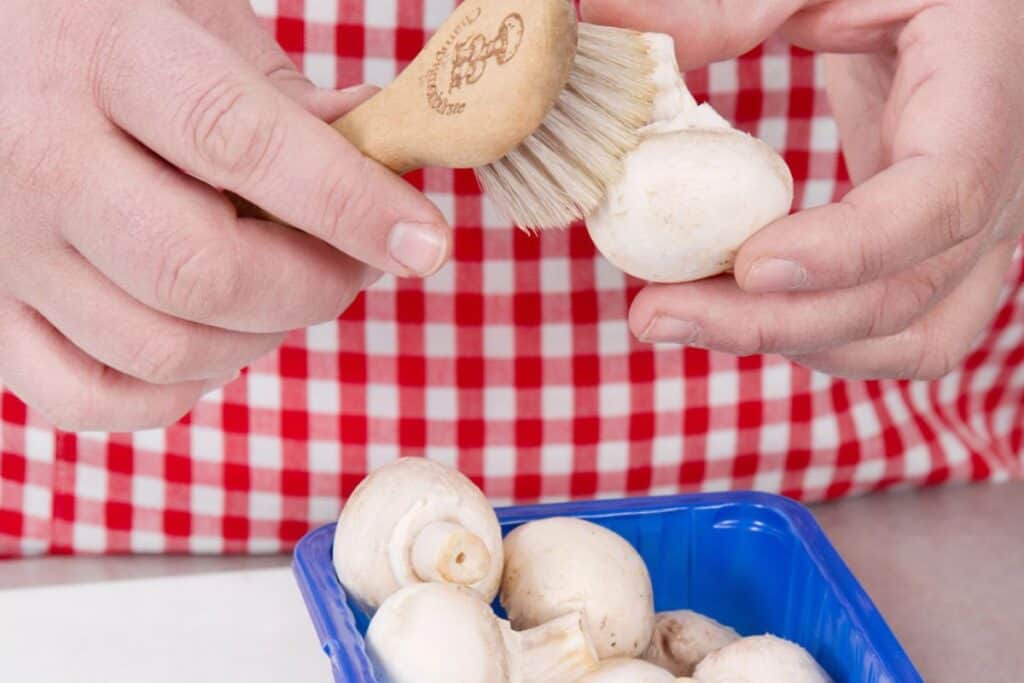 Cleaning mushroom using brush.