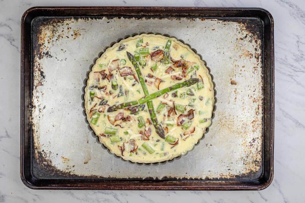 Arrange the asparagus and crumbled bacon evenly in the prepared pie crust.