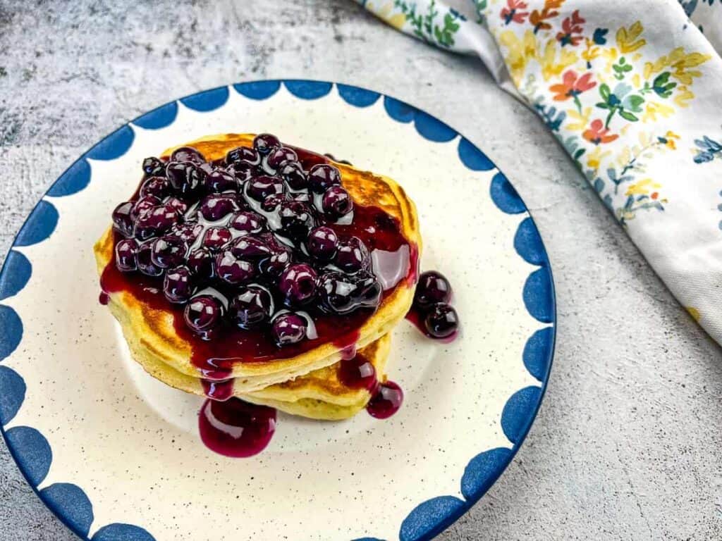 A stack of Blackstone Buttermilk pancakes with blueberry sauce on a plate.
