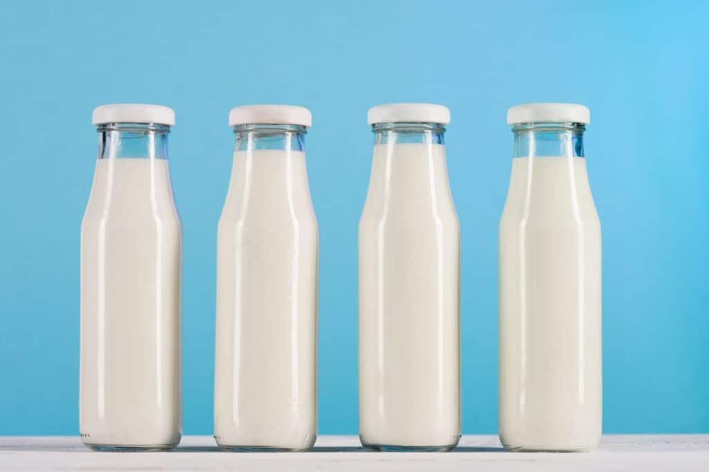 Row of glass bottles with milk on tabletop.