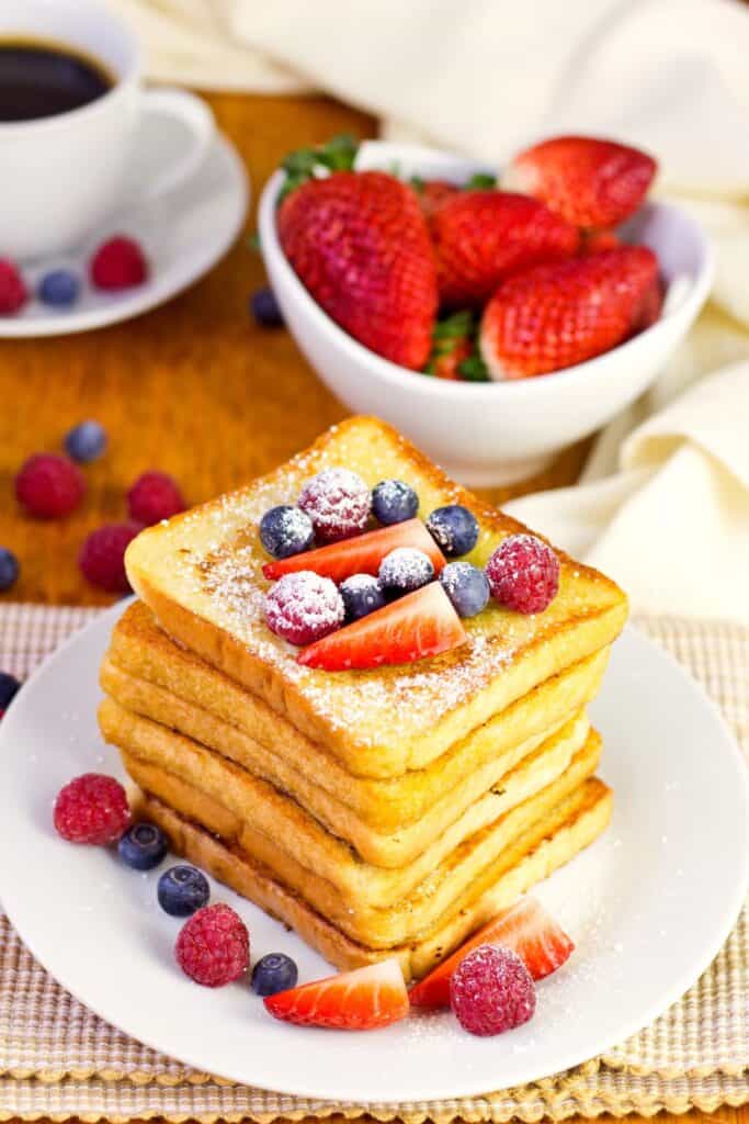 French toast with fruits on a white plate.