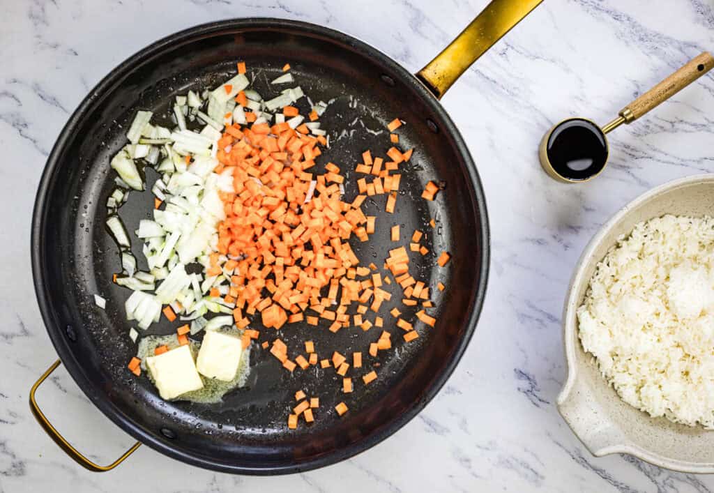 Melt butter with sesame oil in the skillet, add diced carrot and onion, and cook for 3-4 minutes.