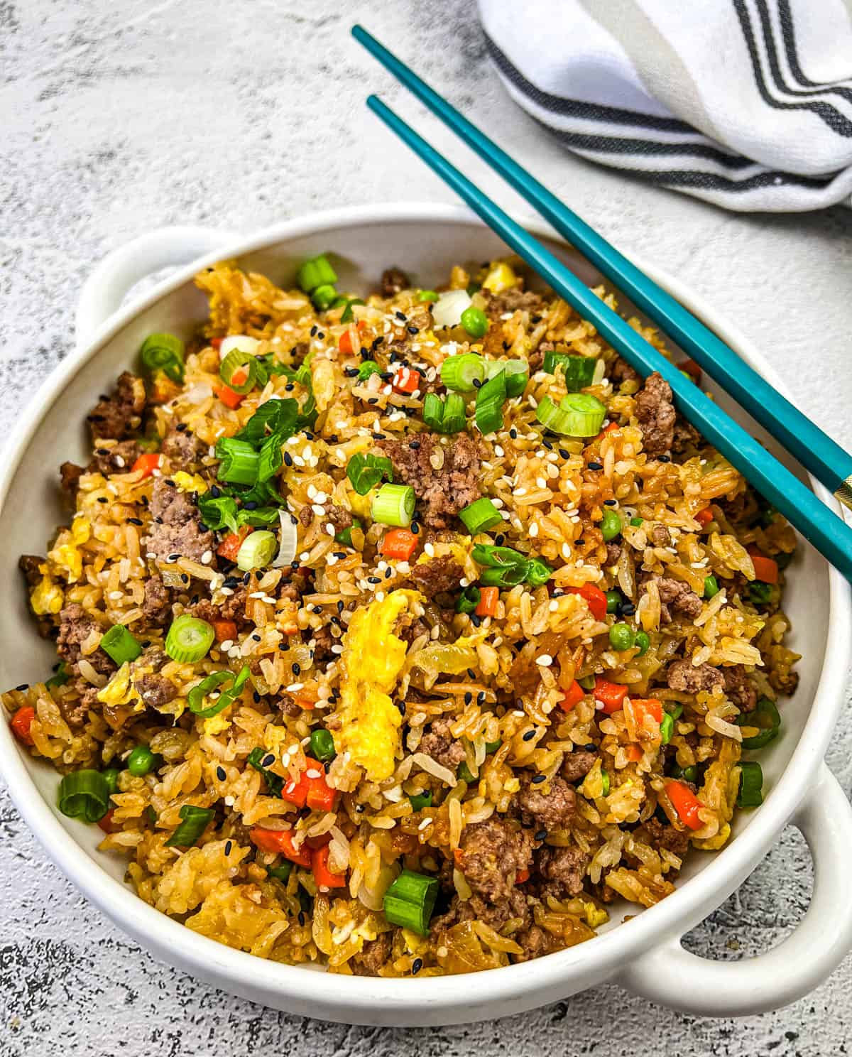 Ground Beef Fried Rice in a white bowl with a pair of chopsticks.