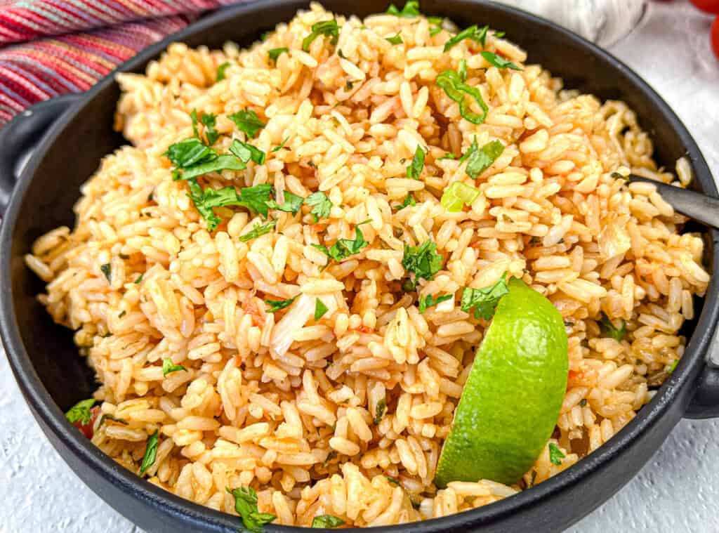 Mexican Rice with a slice of lime on a black dish.