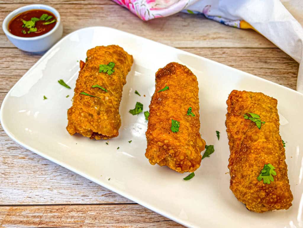 Three pieces of Redneck Eggrolls on a white plate.