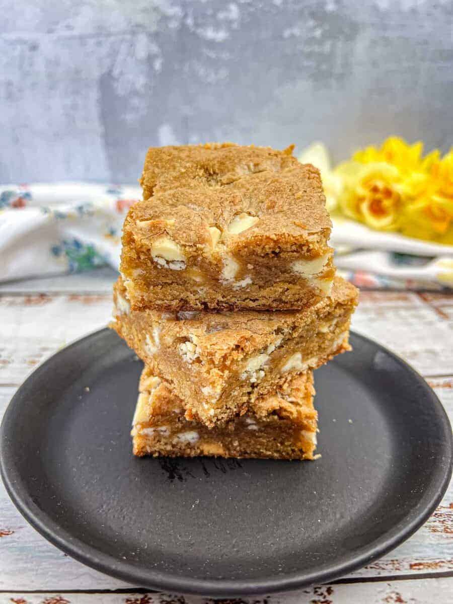 A white plate with four square pieces of Speculoos White Chocolate Blondies bars.