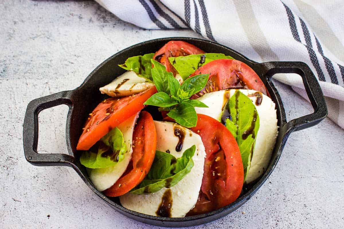 A top-down shot of a classic caprese salad in a black dish.