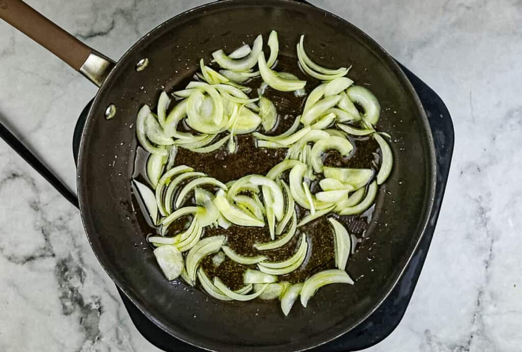 Add the olive oil and sliced onion to a skillet and sauté.