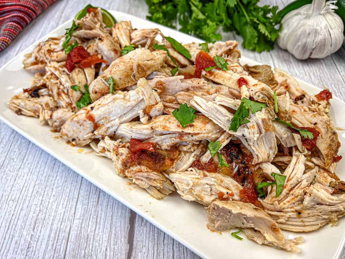 A platter of sheet pan lemon-rosemary chicken with lemon slices, herbs, and garnished with cherry tomatoes.