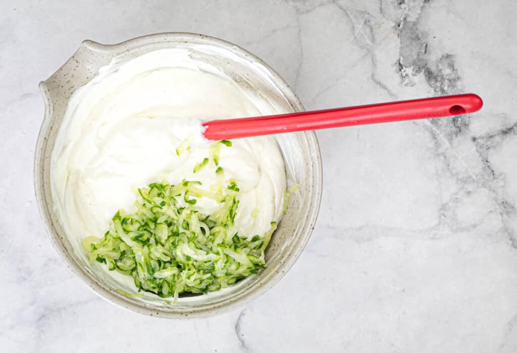 Add the cucumbers to a medium-sized bowl, and add Greek yogurt, minced garlic, olive oil, and lemon juice to the cucumbers.