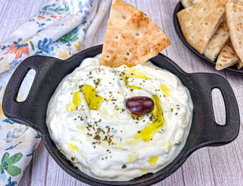 Tzatziki Sauce with pita dipped in a black bowl.