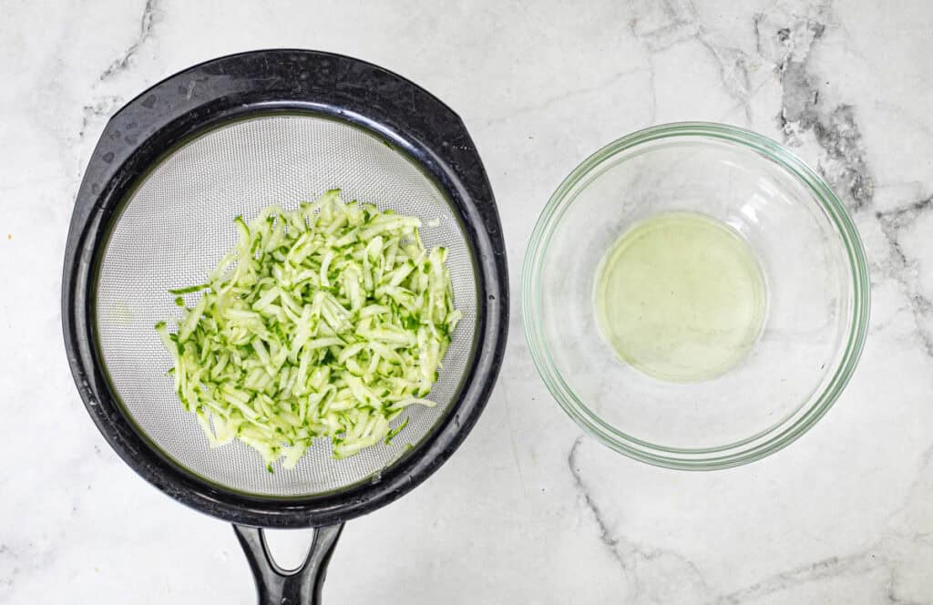 Grate cucumbers using the coarse side of a cheese grater and place them in a strainer.