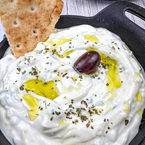 Tzatziki Sauce with pita dipped in a black bowl.