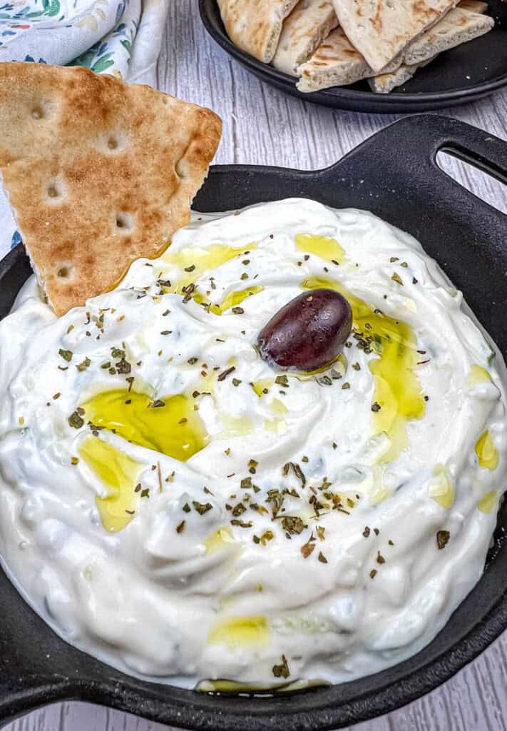 Tzatziki Sauce with pita dipped in a black bowl.