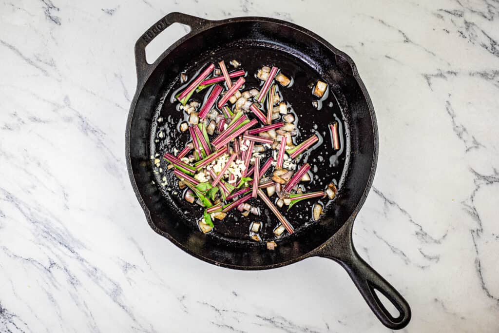 Add the onion, garlic, and beet stems to the skillet and saute.