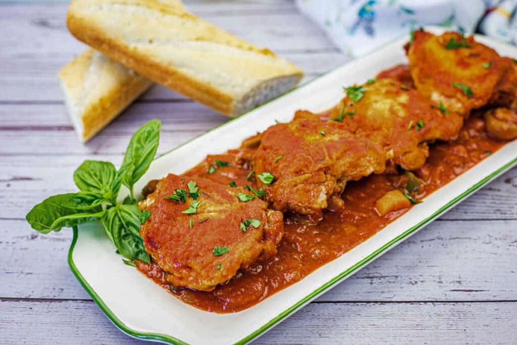 Four pieces of Chicken Cacciatore on a serving platter.