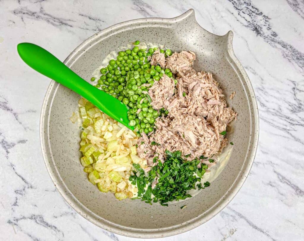 Fold in the sautéed onions and celery, peas, drained tuna, and cooked noodles.