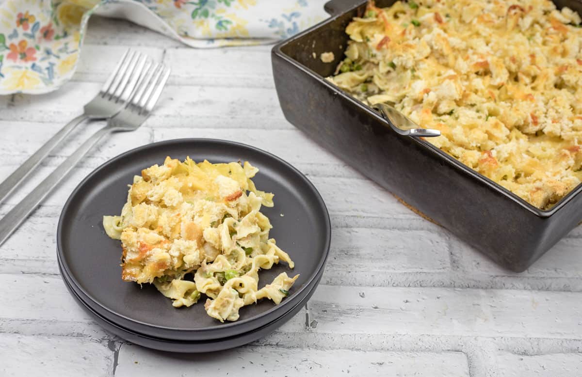 A plate of tuna noodle casserole with more in a baking dish nearby.