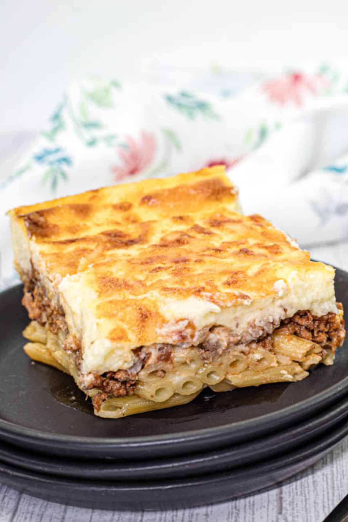 A small portion of Pastitsio on a black plate.