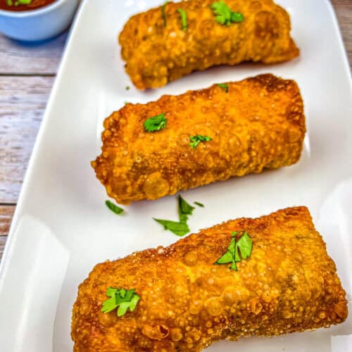 Three pieces of redneck eggrolls on a white plate.