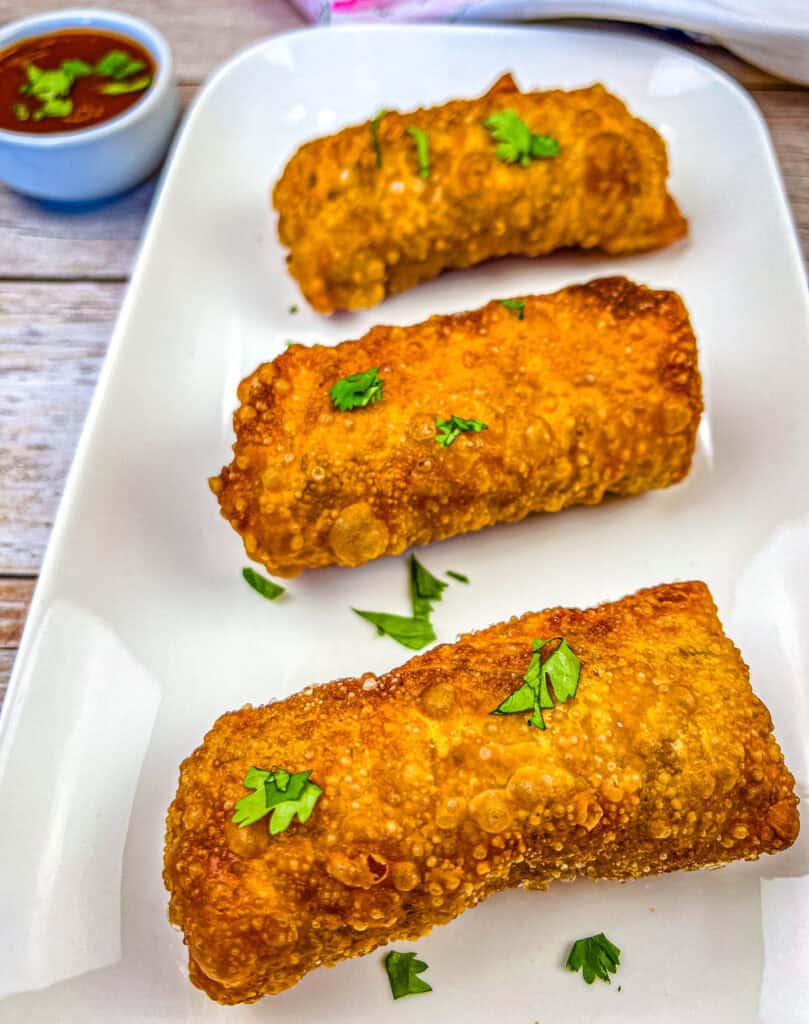 Three pieces of redneck eggrolls on a white plate.